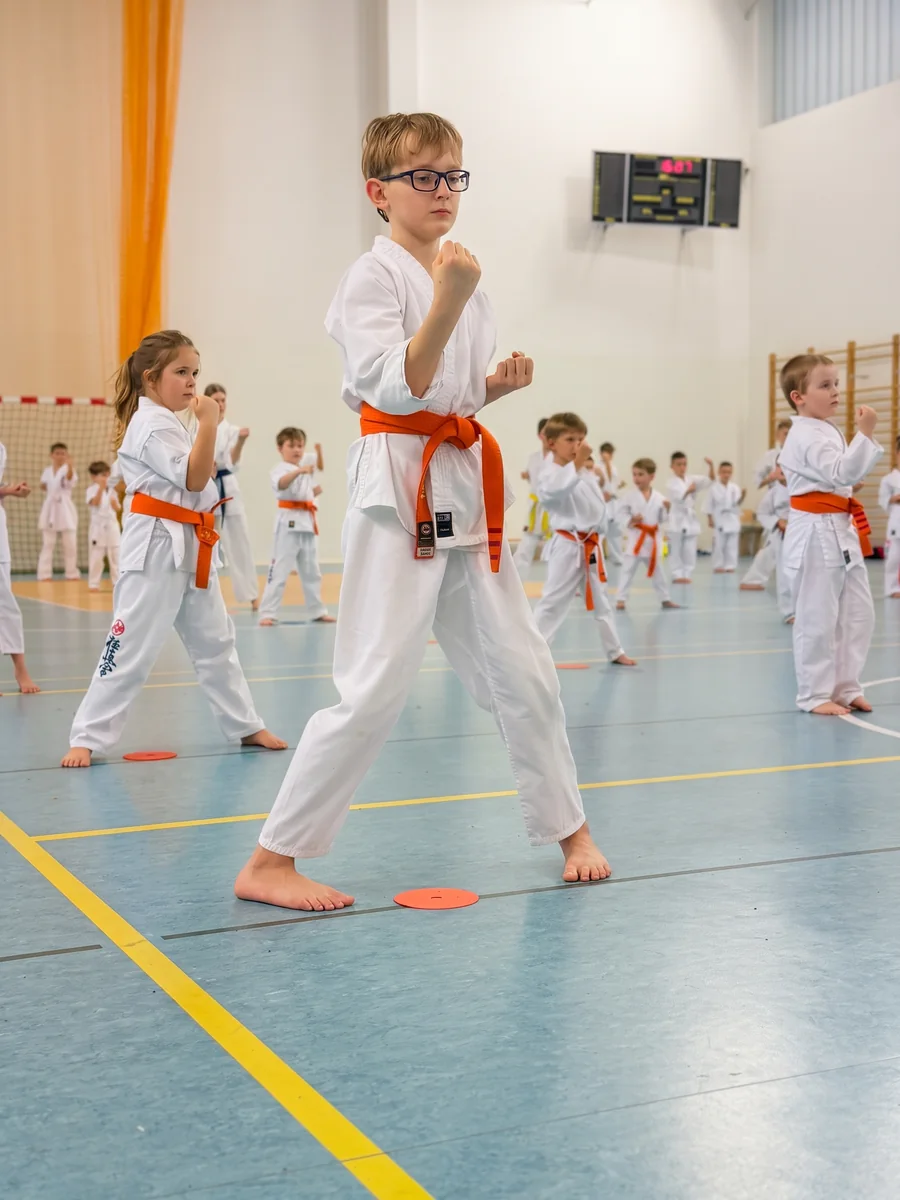 Chłopiec z pomarańczowym pasem w pewnej postawie karate
