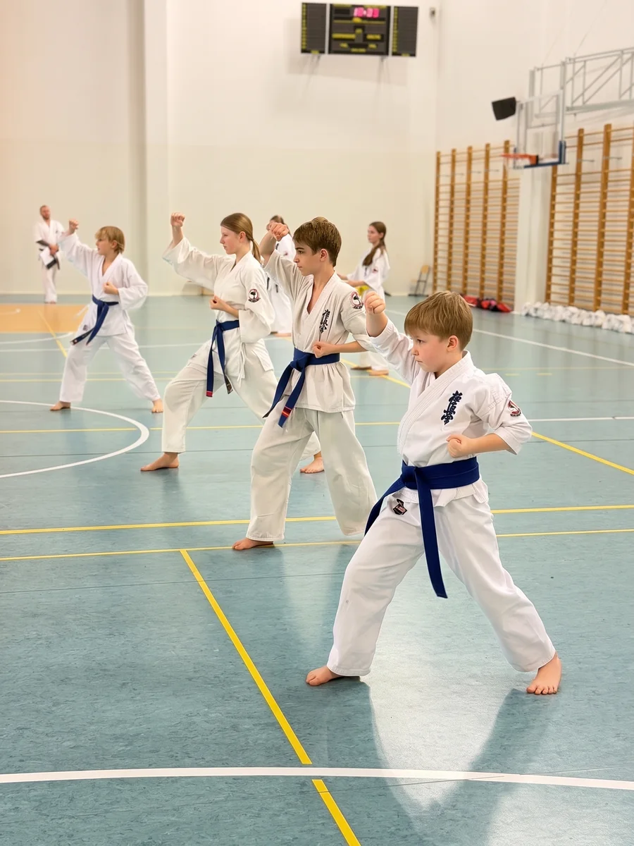 Rząd dzieci w karate gi powtarza technikę za trenerem
