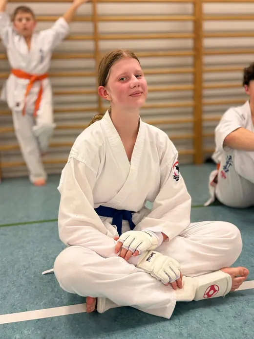 Uśmiechnięta dziewczyna w karate gi po egzaminie