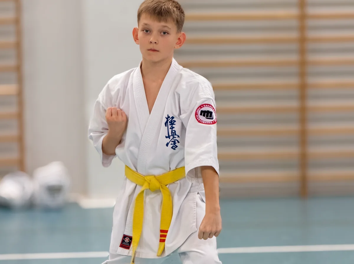 Chłopiec z żółtym pasem w gardzie na treningu karate Kyokushin dla dzieci