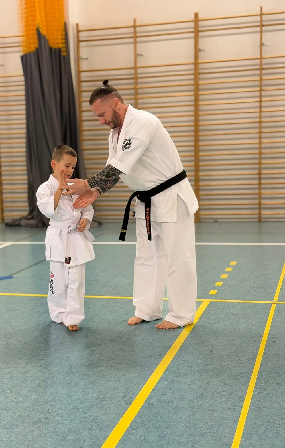Sensei Adam Kopeć z czarnym pasem prowadzi trening dzieci